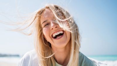 Eine lachende Frau mit vom Wind verwehten Haaren.