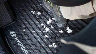 Gummifußmatten mit Schneeresten im vorderen Innenraum eines Hyundai Fahrzeugs. 