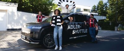 Ein Hyundai IONIQ 9 – umgeben von in Fanschals und Trikots gekleideten Eintracht Frankfurt Fans. 