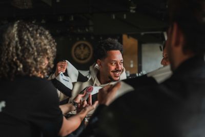 Ein Gruppe von Menschen bewundern den Eintracht Frankfurt Schal eines Eintracht Fans. 