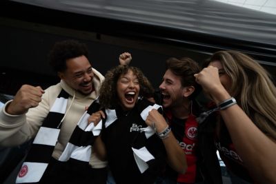 Jubelnde, in Fanschals gekleidete Eintracht Frankfurt Fans. 