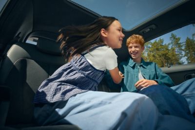 Zwei Kinder albern ausgelassen auf dem Rücksitzt eines Hyundai Elektrofahrzeuges
