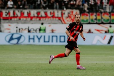 Mario Götze läuft im Eintracht Trikot vor einer Hyundai Bande im Stadion entlang.