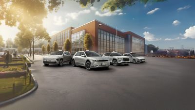  Mehrere Hyundai Modelle als Fahrschulwagen stehen nebeneinander vor einem großen Gebäude.