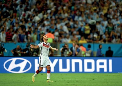 Der Eintracht-Spieler Mario Götze läuft im Deutschland-Trikot über ein Fußballfeld mit ausgebreiteten Armen und Blick nach oben.