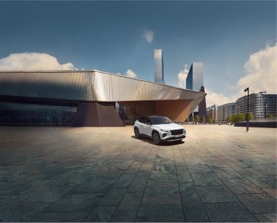 Der Hyundai TUCSON stehend auf einem Platz vor einem großen Gebäude.