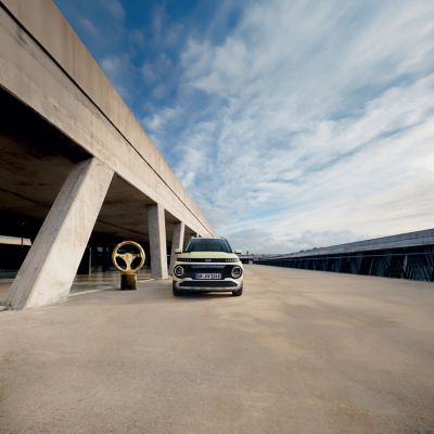 Ein Hyundai INSTER, der vor einer futuristischen Fassade parkt.