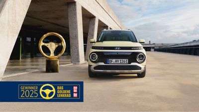 Ein Hyundai INSTER parkt vor einem modernen Gebäude.