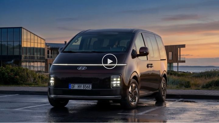 Ein Hyundai STARIA Elektro steht vor modernen Strandhäusern bei Sonnenuntergang