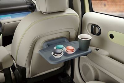 Gebäck und ein Kaffee auf einem Ausklapptisch eines Hyundai INSTER. 
