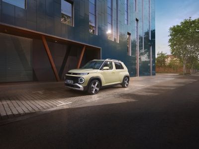 Ein Hyundai INSTER, der vor einer futuristischen Fassade parkt.