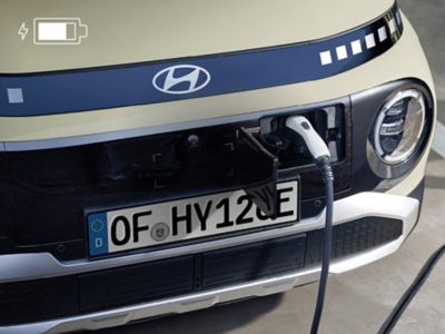 Detailansicht eines Ladeanschlusses des Hyundai INSTER mit eingestecktem Ladestecker.