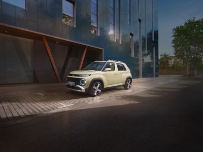 Ein Hyundai INSTER parkt vor einem modernen Gebäude.