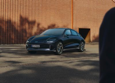 Der Hyundai IONIQ 6 parkt vor einer großflächigen Häuserfassade.