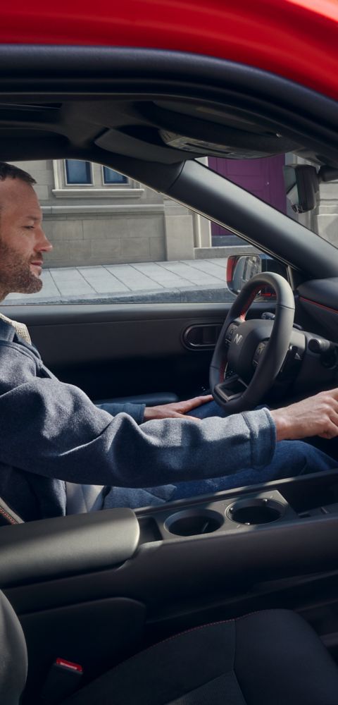 Ein Mann sitzt im Hyundai IONIQ 3 und bedient das  Infotainmentsystem Pleos Connect.