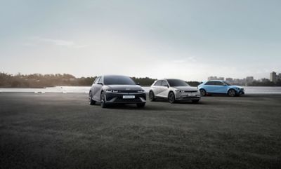Ein Hyundai IONIQ 5 N Line, IONIQ 5 und IONIQ 5 N parken vor einer urbanen Skyline.