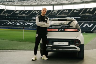Mario Götze steht im Deutsche Bank Park Stadion neben einem Hyundai INSTER. 