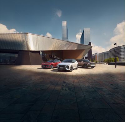 Ein grüner Hyundai IONIQ 9 parkt vor einem modernen Gebäude und lädt. 