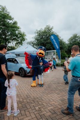 Ein Kind posiert mit dem Hyundai Verkehrs-Maskottchen Fredi im LEGOLAND® Deutschland Resort vor einem Hyundai IONIQ 5 N.