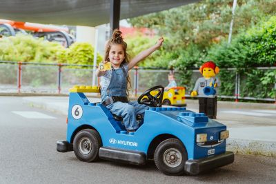 Ein Mädchen in einem Fahrzeug der Legoland Junior Fahrschule powered by Hyundai zeigt ihren Führerschein.