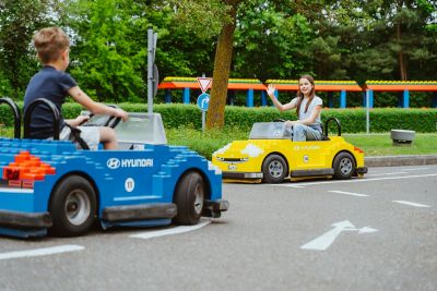 Zwei Kinder in Fahrzeugen der Legoland Fahrschule powered by Hyundai fahren auf dem Fahrschulparcours.
