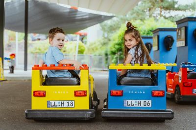 Rückansicht zweier Fahrzeuge der Legoland Junior Fahrschule powered by Hyundai, die darin sitzenden Kinder drehen sich nach hinten um.