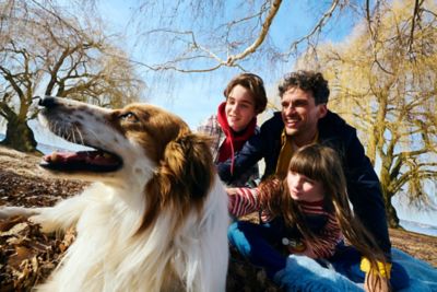 Ein Vater streichelt gemeinsam mit seinem Sohn und seiner Tochter einen Hund.