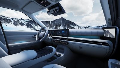 Blick in das vordere Interieur eines in einer Schneelandschaft parkenden Hyundai NEXO mit Lenkrad, Displays und Bedienelementen.
