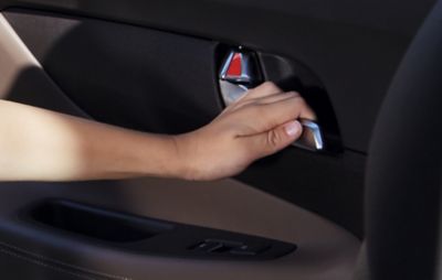 Eine Kinderhand betätigt den Hebel einer Tür im Innern eines Hyundai TUCSON.
