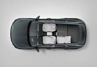 Eine Frau belädt vor einer Gebirgskulisse den Gepäckraum eines Hyundai TUCSON.