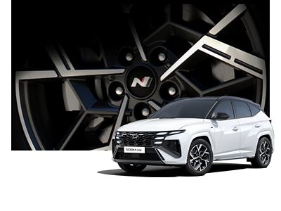 Ein weißer Hyundai TUCSON N Line vor einem vergrößerten Detail einer N Line Felge. 