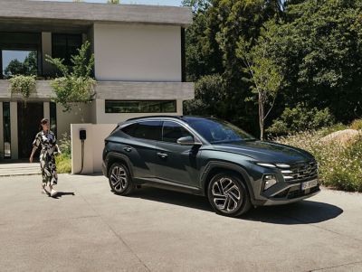 Der Hyundai TUCSON Plug-in-Hybrid stand vor einem großen Haus. 