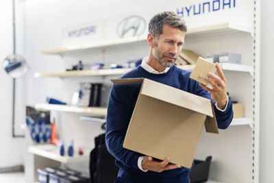 Ein Hyundai Servicemitarbeiter räumt Hyundai Originalteile und Pflegemittel in ein Regal.