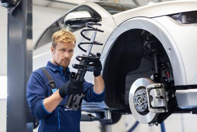 Ein Hyundai Mechaniker an der Hebebühne hält das Federbein eines Hyundai in der Hand. 
