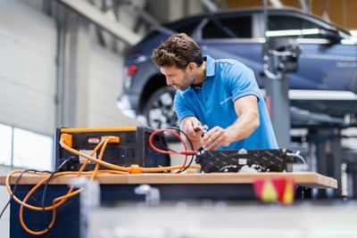 Ein Hyundai Servicemitarbeiter beim Check einer Starterbatterie in der Werkstatt.