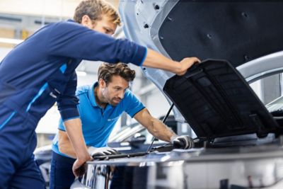 Zwei Hyundai Servicemitarbeiter begutachten in der Werkstatt den Motorraum eines Hyundai.