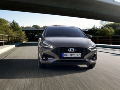 Frontansicht des Hyundai i30 Wagon in Grau, der unter einer Autobahnbrücke hindurchfährt.