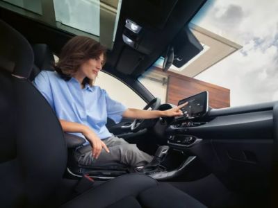 Eine Frau tippt auf den 10.25-Zoll-Touchscreen des Hyundai i30.