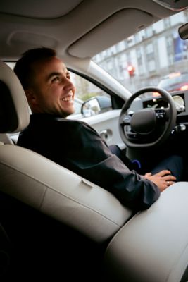 Fußbalprofi Mario Götze sitzt lächelnd auf dem Fahrersitz eines geparkten Hyundai.