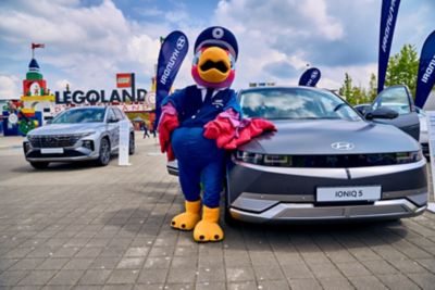 Der Hyundai IONIQ 5 mit dem Hyundai Maskottchen „Fredi“ vor dem Eingang des LEGOLAND® Deutschland Resort.