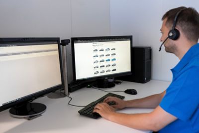 Ein Online-Showroom-Mitarbeiter an seinem Arbeitsplatz mit auf dem Bildschirm angezeigten Hyundai-Modellen.