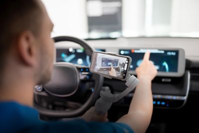 Ein Hyundai Showroom-Berater mit Headset und Kamera filmt und erklärt das Interieur eines Hyundai.