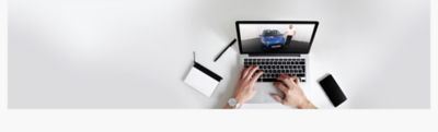 Ein Laptop von oben gesehen. Der Bildschirm zeigt einen Presenter des Hyundai Online-Showroom.