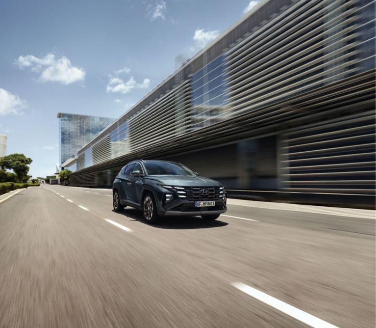 Zelený Hyundai TUCSON Hybrid jazdiaci v meste