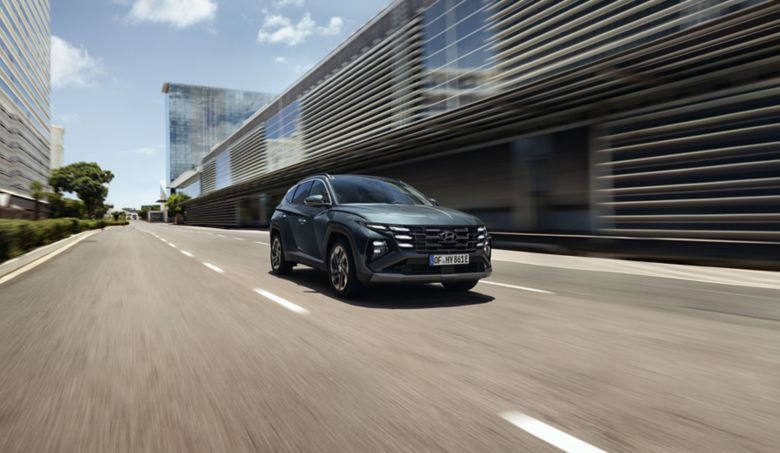 Zelený Hyundai TUCSON Hybrid jazdiaci v meste