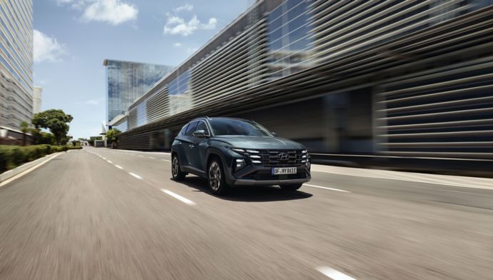 Zelený Hyundai TUCSON Hybrid jazdiaci v meste