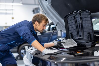 Servisní technik stojící před otevřenou kapotou.