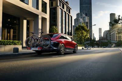 Röd Hyundai IONIQ 6 med cykelhållare bak, som illustrerar Hyundai Holiday Check inför sommarresan.