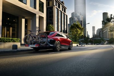 Röd Hyundai IONIQ 6 utrustad med cykelhållare för dragkrok och två cyklar.