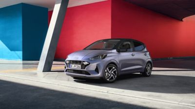 Hyundai i10 est garée devant un mur rouge et bleu.